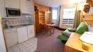 Et kompakt værelse med tekøkken, spiseplads og sofa.