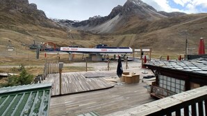 En træterrasse med udsigt til et bjerglandskab og en tankstation i baggrunden.
