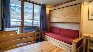 Et værelse med et træbord, en rød sofa og et vindue med udsigt til bjerge.