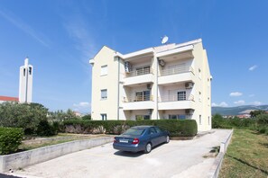 A multi-story residential building with a car parked in front. - Summer Seaside Pearl Apartment Kastela (Kastela)