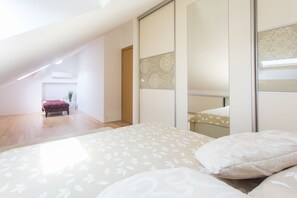 A bedroom with a large bed, a wooden floor, a sliding door, and a small table with a plant. - Summer Seaside Pearl Apartment Kastela (Kastela)