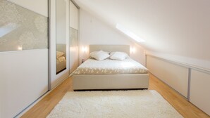 Un dormitorio con cama, alfombra blanca y tragaluz.