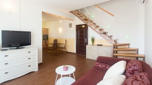 Una sala de estar moderna con televisor, sofá y escalera.