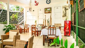 A dining area with wicker furniture, a white tablecloth-covered table, and potted plants. - VAL HOTEL MANUEL ANTONIO (Quepos)