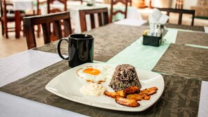 A dining table with a plate of food, a black mug, and a small black container. - VAL HOTEL MANUEL ANTONIO (Quepos)
