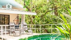 A pool area with lounge chairs and a covered seating area, surrounded by lush greenery. - VAL HOTEL MANUEL ANTONIO (Quepos)