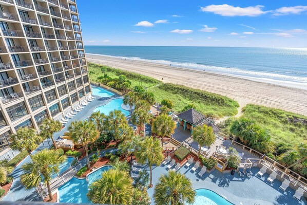 A hotel with a pool area, beach view, and a high-rise building.