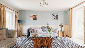 Un salón con sofá, una mesa de centro con adorno decorativo, una araña y obras de arte en las paredes.