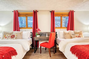 Hotellihuone, jossa on kaksi sänkyä, työpöytä ja tuoli.