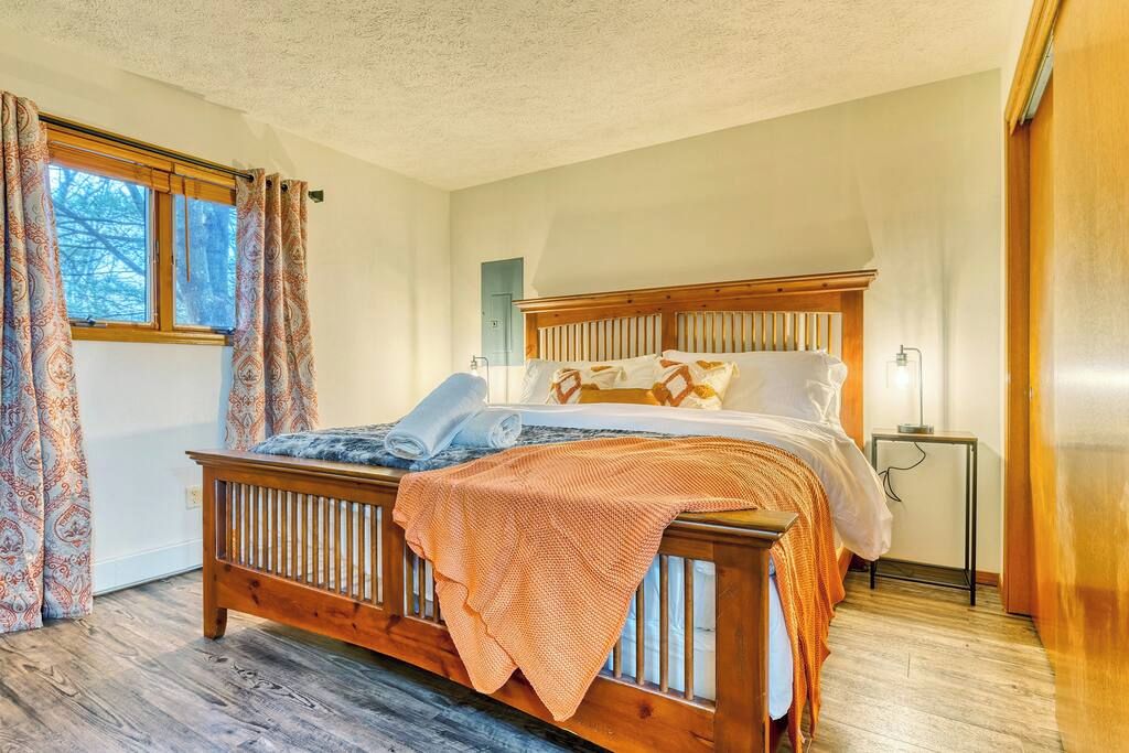 Een slaapkamer met een houten bed, gordijnen met een patroon en een nachtkastje.