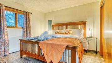 Een slaapkamer met een houten bed, gordijnen met een patroon en een nachtkastje.
