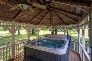 A covered hot tub area with a wooden ceiling and white railings.