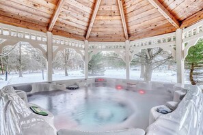 Un bain à remous sous une pergola en bois, avec vue sur un paysage enneigé.