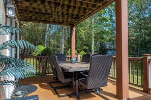 Une terrasse extérieure avec une table et des chaises, entourée d’une plateforme en bois et d’une rambarde.