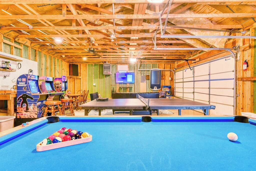 Un espace de loisirs intérieur comprenant une table de billard, des billes de billard et des jeux d’arcade.