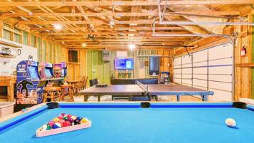 Un espace de loisirs intérieur comprenant une table de billard, des billes de billard et des jeux d’arcade.