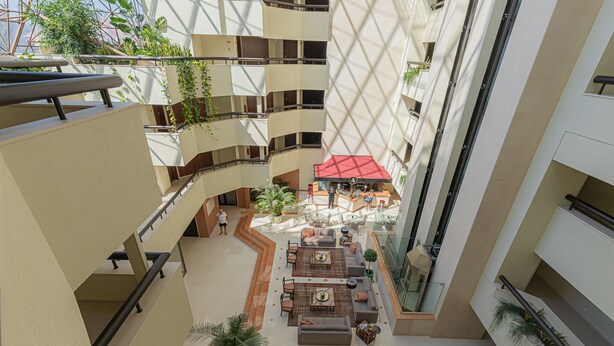 Een meerlaagse atrium met een centraal zitgedeelte, balkons en kamerplanten.