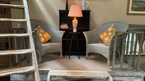 A cozy room with wicker furniture, a lamp, and a bookshelf.