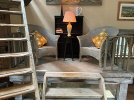 Una habitación acogedora con muebles de mimbre, una lámpara y una estantería.