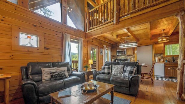 A cozy cabin interior with two leather sofas, a wooden coffee table, and a kitchen area with a microwave. - Nice View! Log Cabin,Fireplace,Hot Tub,Pool Table (Sevierville)
