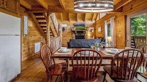 A wooden cabin interior with a dining area, a fireplace, and a television. - Nice View! Log Cabin,Fireplace,Hot Tub,Pool Table (Sevierville)