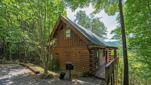 A rustic log cabin with a porch, surrounded by dense forest. - Nice View! Log Cabin,Fireplace,Hot Tub,Pool Table (Sevierville)