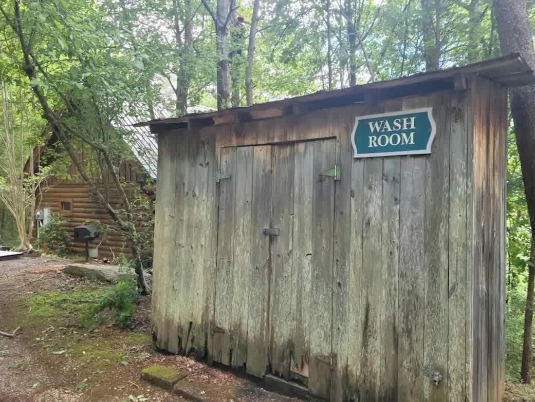 A rustic wooden washroom with a sign.