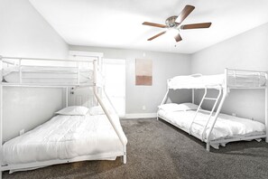 Una habitación con literas, ventilador de techo y una puerta.