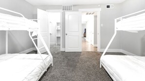A bedroom with bunk beds, a door, a ceiling fan, and a carpeted floor.