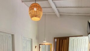 A spacious room with a large woven rug, a wooden bench, and a small sink area. - Pousada Sol Nascente Caraíva (Porto Seguro)
