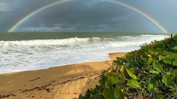 A beach with waves, a rainbow, and overcast sky. - Pousada Sol Nascente Caraíva (Porto Seguro)