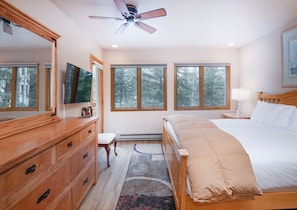 Un dormitorio con cama, cómoda, tocador y ventilador de techo.