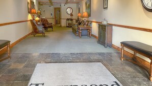 A hotel lobby with a 'Townsend Place' carpet, a reception desk, leather chairs, a clock, and a mirror on the wall. - Mountain Modern Beaver Creek Village Condo, Ski-In and Out, w/ Hot Tub and Views (Beaver Creek)