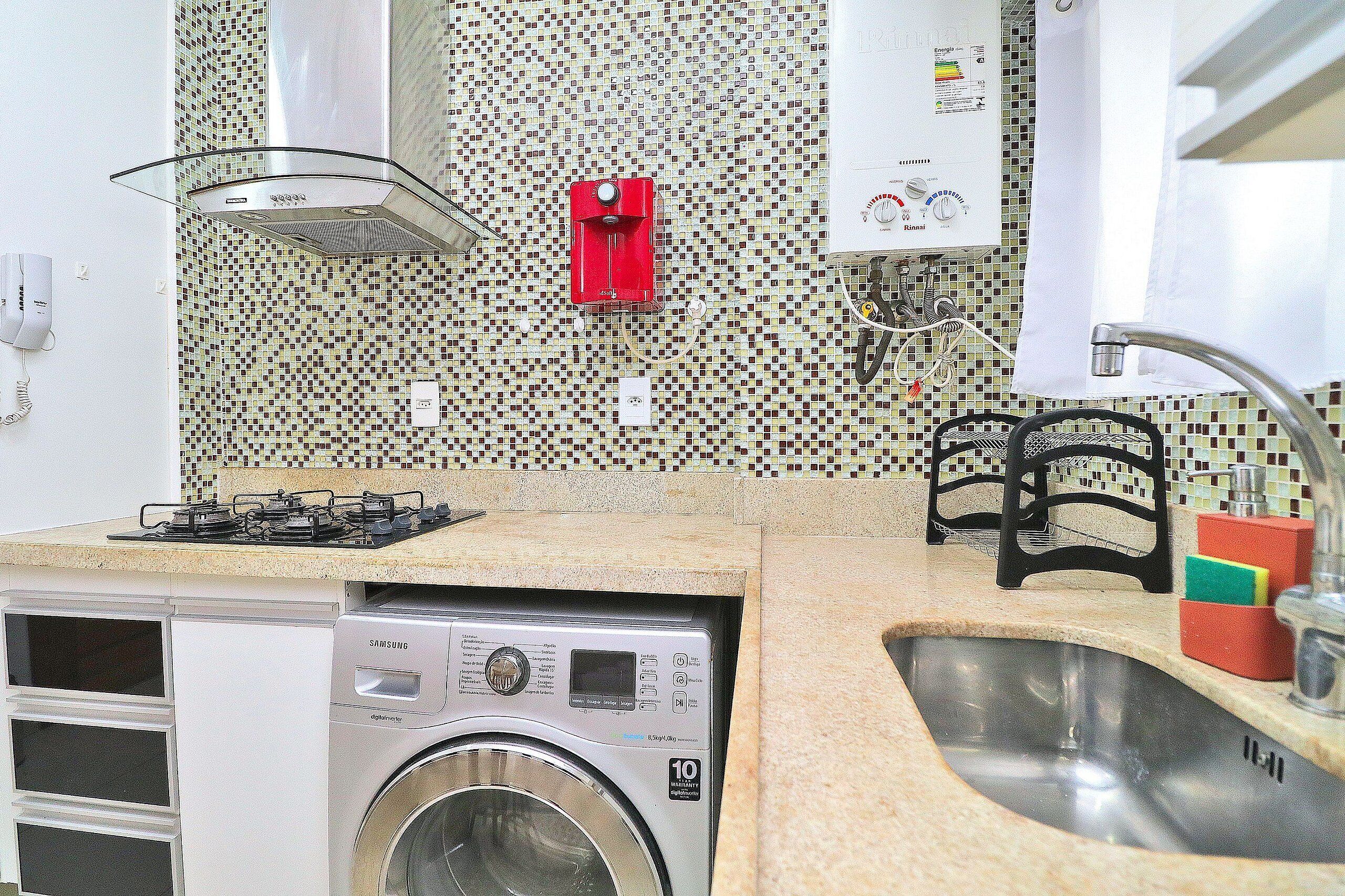A compact kitchen with a washing machine, a gas stove, and a sink.