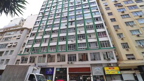 A multi-story building with numerous windows and balconies, featuring a green structural frame. - Rio Spot Homes MC C055 (Rio de Janeiro)