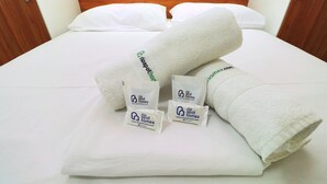 A neatly made bed with white linens and two rolled towels with a logo and website address. - Rio Spot Homes MC C055 (Rio de Janeiro)