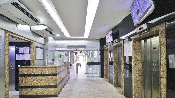 A reception area with a reception desk, a digital display, and an elevator. - Rio Spot Homes MC C055 (Rio de Janeiro)