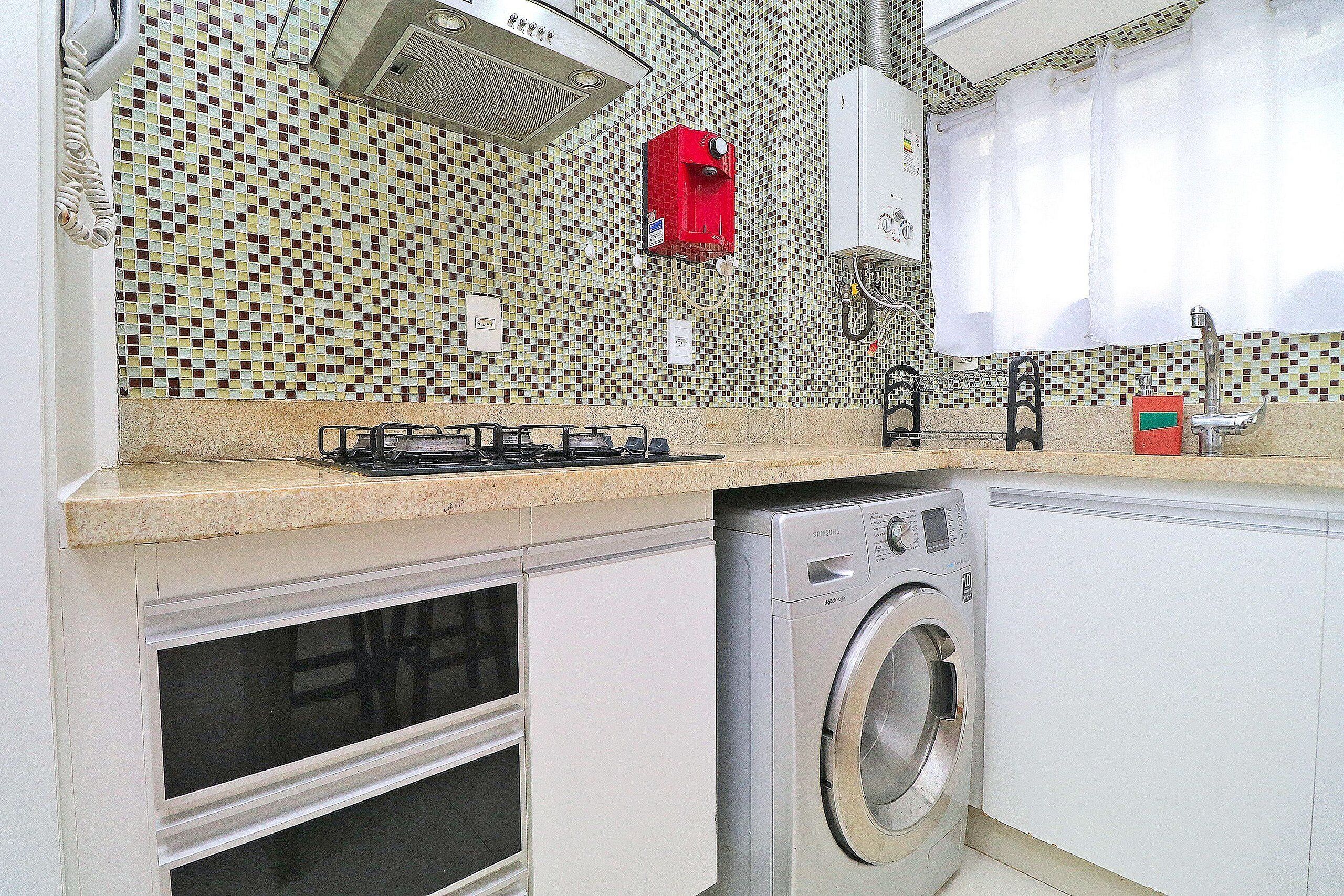 Una cocina con lavadora, estufa y salpicadero de azulejos.