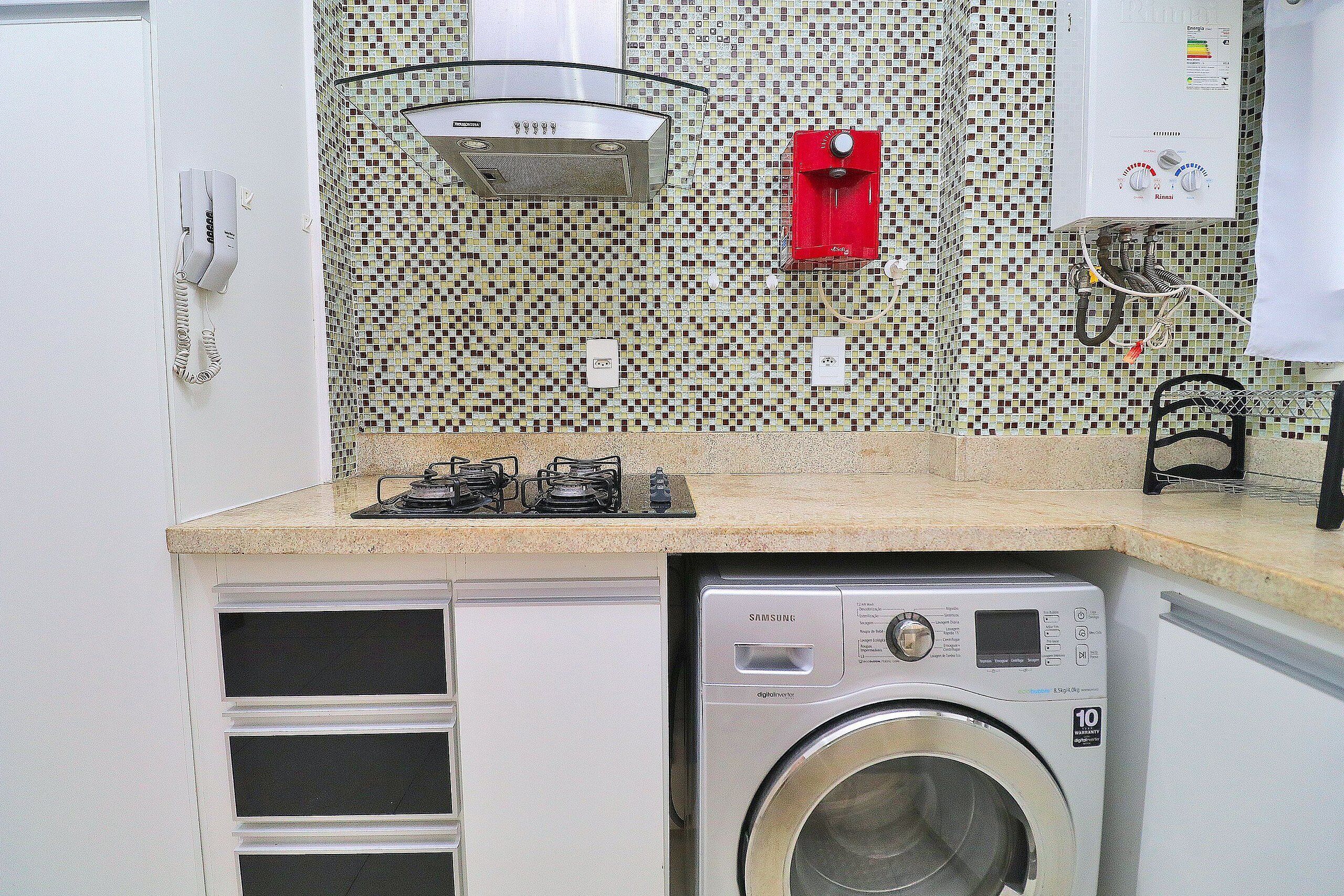 A compact kitchen with a built-in washing machine, a gas stove, and a telephone.