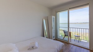 A hotel room with a bed, a balcony with a chair and table, and a view of the sea. - Le Flamingo - Première conciergerie (Palavas-les-Flots)