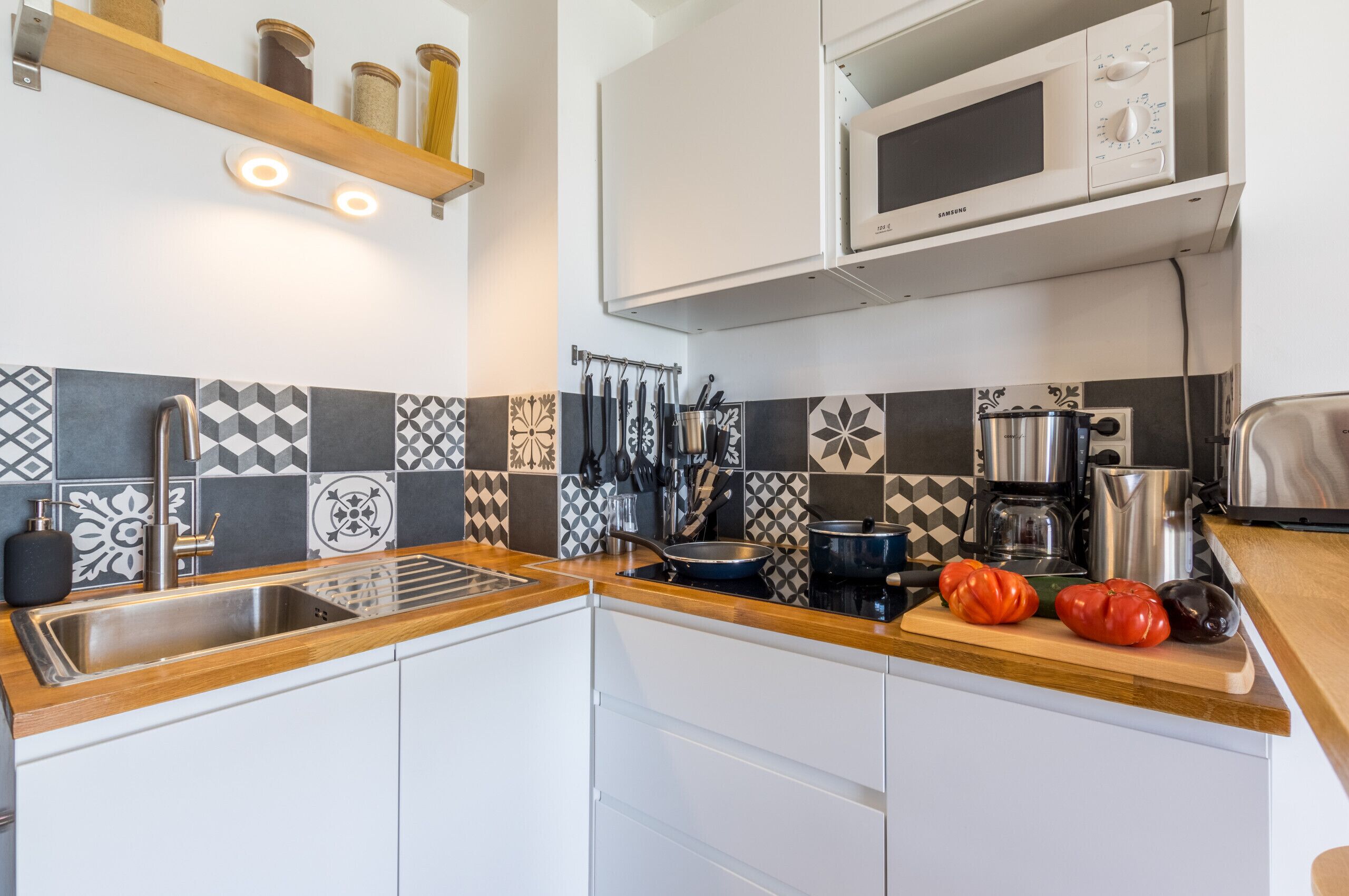 Una cocina moderna con un lavamanos de acero inoxidable, un microondas y una cafetera.
