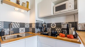 A modern kitchen with a stainless steel sink, a microwave, and a coffee maker. - Le Flamingo - Première conciergerie (Palavas-les-Flots)