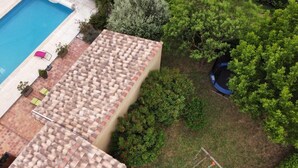 Ovenudblik over en ejendom med swimmingpool, tennisbane og overdækket patio.
