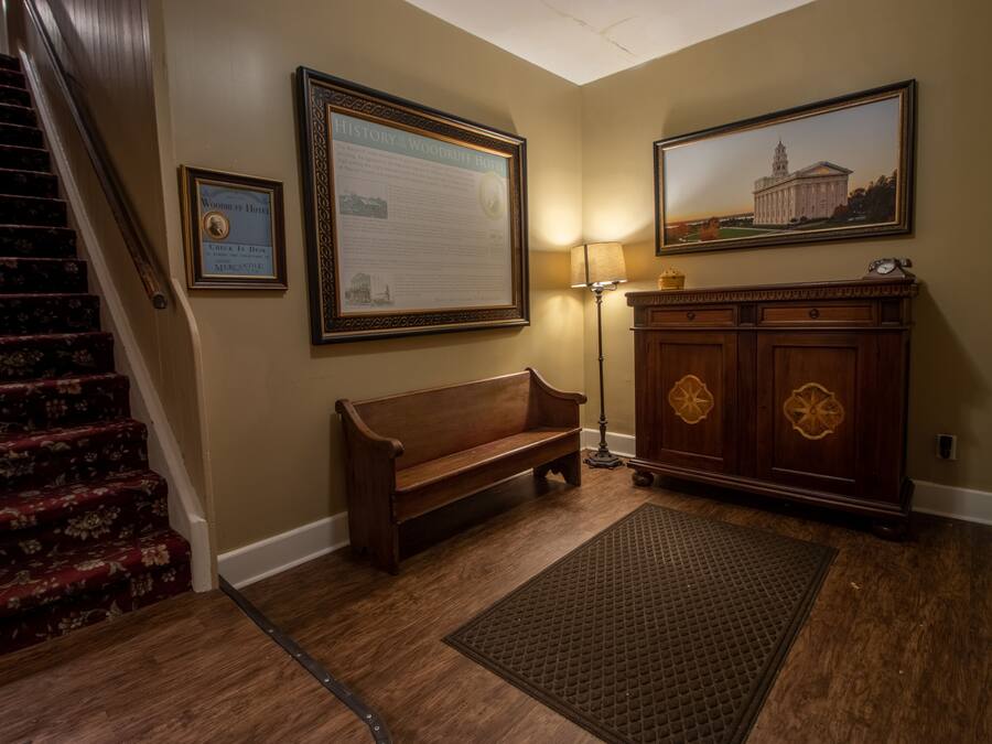 A wooden bench, a framed history plaque, a lamp, and a painting on the wall.