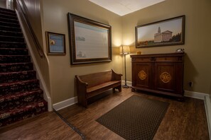 A wooden bench, a framed history plaque, a lamp, and a painting on the wall. - Nauvoo Temple House Hotel (Nauvoo)