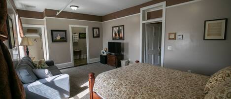 A bedroom with a bed, a sofa, a television, and a desk.