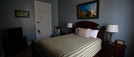 Une chambre à coucher comprenant un lit, des tables de chevet, un téléviseur et un ventilateur de plafond.