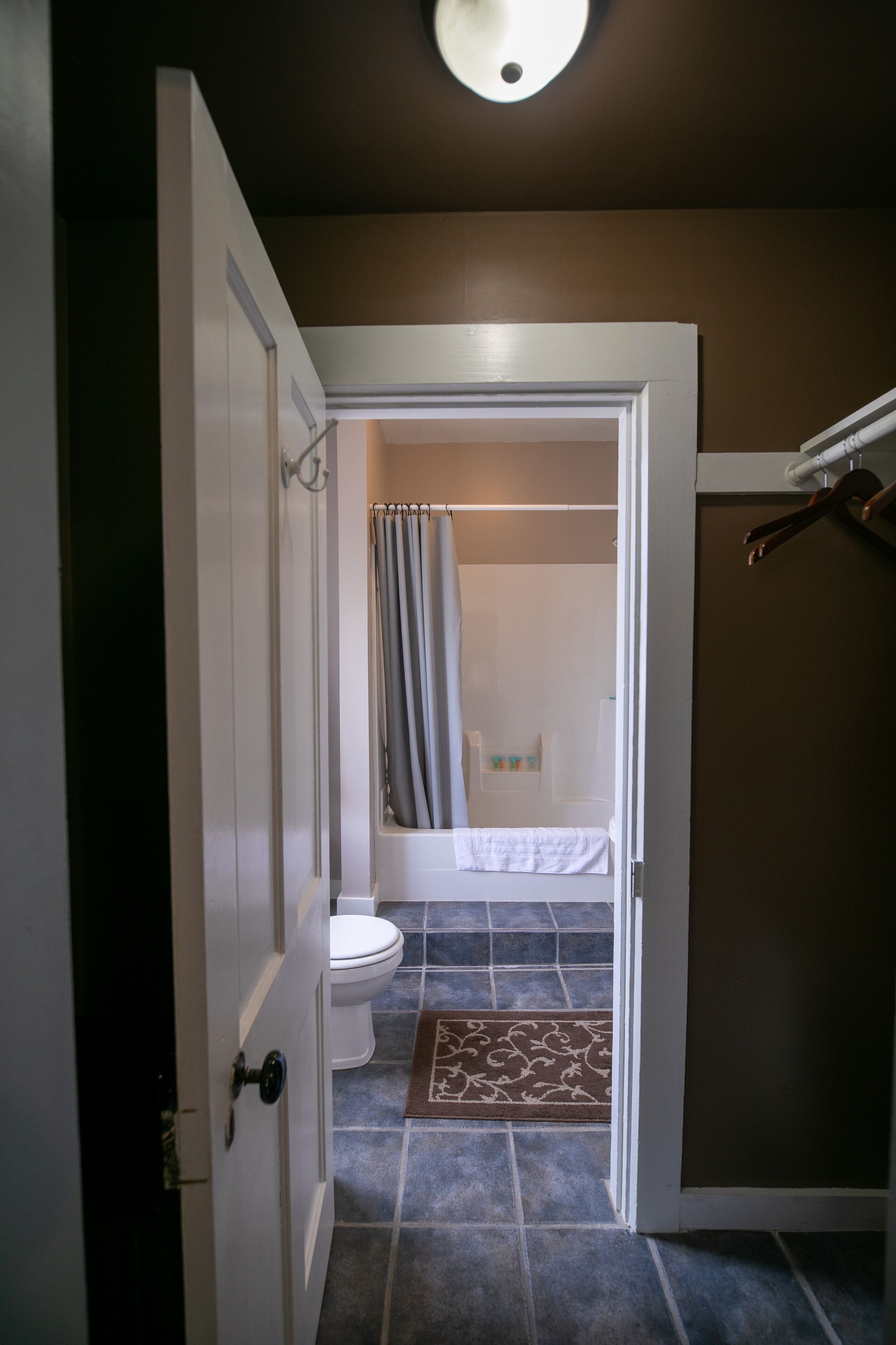 A bathroom with a toilet, shower, and a towel rack.