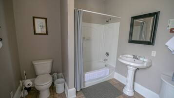Une salle de bain équipée de toilettes, d’une douche, d’un lavabo et d’un tableau encadré au mur.