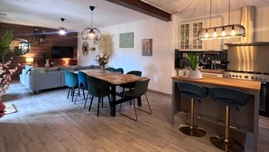 A modern kitchen with a central island, bar stools, and a dining area with a wooden table and chairs. - Maison idéale pour les familles avec piscine privée - Fontaine-de-Vaucluse (Fontaine-de-Vaucluse)